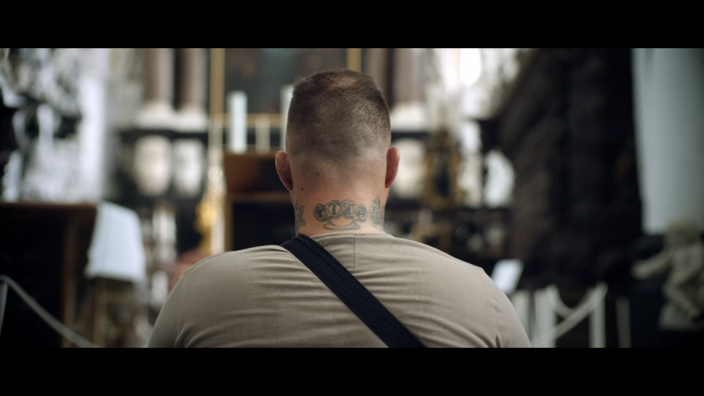Franky's achterhoofd en nek met tattoo in een kerk